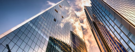 Looking up in between two clear windowed skyscrapers