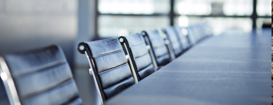 Row of black ribbed leather office chairs next to a long conference table