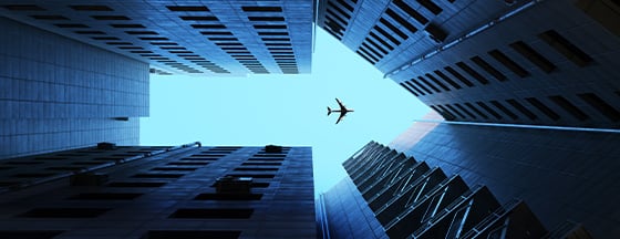 low-angle photograph looking up at skyscrapers with an airplane flying overhead